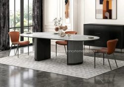 Fancy Homes Large Aubrey oval sintered stone dining table with a glossy sintered stone top and a fluted light and dark grey metal pedestal base, shown with tan leather chairs in a modern luxury interior.