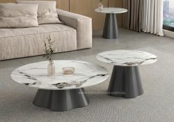 Fancy Homes contemporary nesting set of Kove round coffee and side tables featuring white sintered stone tops with bold charcoal and gold veining on sculptural dark grey fluted bases, styled in a minimalist living room.