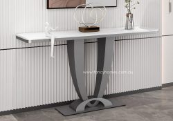 Side view of the luxurious Fancy Homes Senza Sintered Stone Console Table positioned against a white fluted wall. The table features a slim white marble-effect top and a sculptural dark grey stainless steel base, showcasing a high-end minimalist interior design.