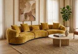 Veloura-b modern curved modular fabric sofa in luxurious mustard gold upholstery, featured in a contemporary sunlit living room.